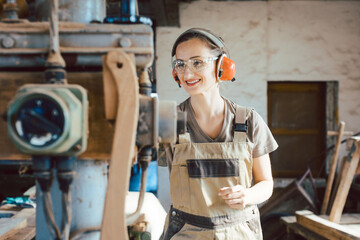 Woman carpenter in traditional carpentry adjusting the machine planer by hand