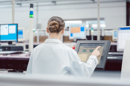Woman on control compute of assembly line in electronics factory