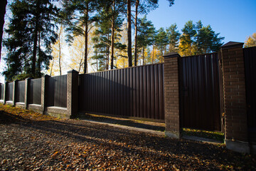 Garden fencing. A metal fence with a sliding door fixed to brick posts.
