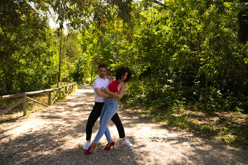 Handsome young man and woman dancing bachata and salsa in the park. The couple dance passionately surrounded by greenery. Dancing concept.