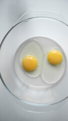 Two broken eggs in a transparent plate. The concept of yin yang is the birth of life