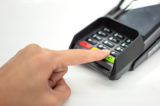 Person hand is pressing the enter button to confirm payment transaction on the credit card reader device. Business and technology action scene photo, selective focus.