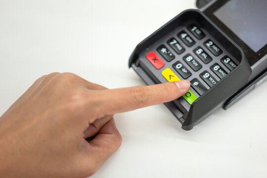 Person hand is pressing the enter button to confirm payment transaction on the credit card reader device. Business and technology action scene photo, selective focus.