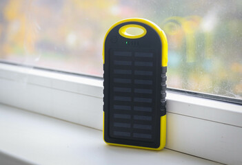 A yellow power bank with a solar battery during the day