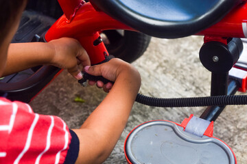 Obraz premium Kid boy repairing his red bicycle at park