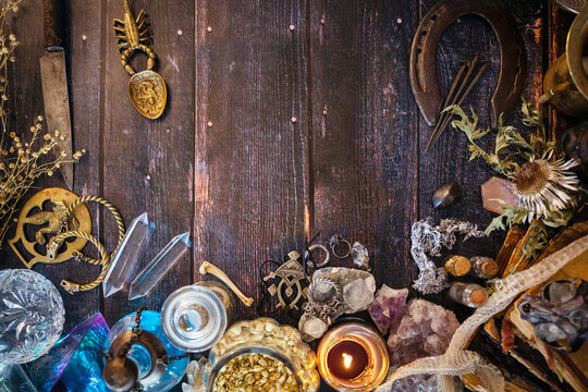 Occult altar with cristals, snake skin, jewellery,potions, herbs,  bones and old books. Esoteric, pagan, Wicca, witchcraft background with magical objects. Halloween concept. Top view, copy space.