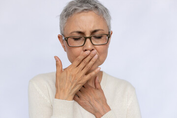 Close-up of senior woman smelling palm checking her breath. Mature Caucasian woman wearing...
