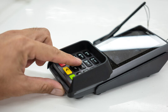 Person hand is pressing the enter button to confirm payment transaction on the credit card reader device. Business and technology action scene photo, selective focus.