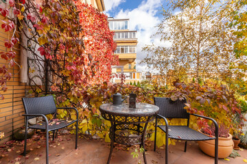 Outdoor terrace with garden furniture on a sunny autumn day. A bright landscape of golden autumn.