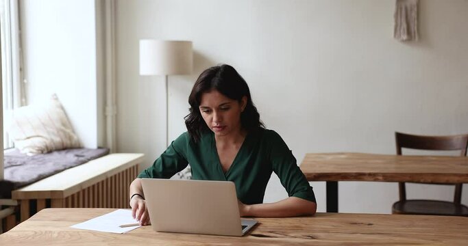 Woman sit at desk with laptop, search information on internet, jotting, making notes, working or studying in office. Modern technology usage for gaining new skill, use on-line resources for e-learning