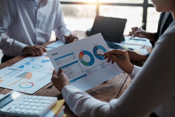 Business people meeting to plan, analyze and point to graphs and charts about business growth to plan new business expansions in the future.