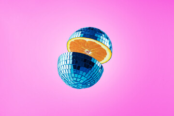 Cut disco ball with orange inside on purple background. Creative fruit collage.