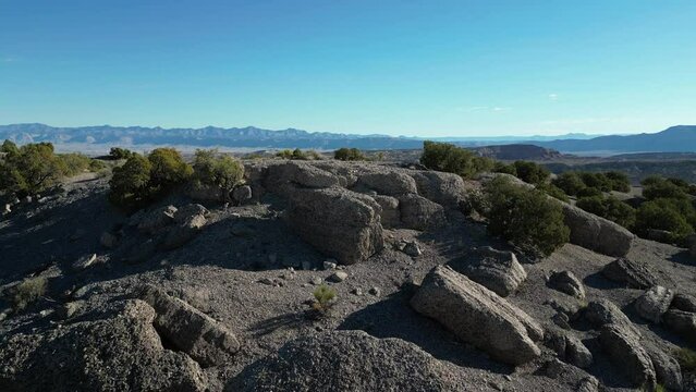 Fast aerial above granite boulders and pinyon pine in Central Utah grey desert landscape