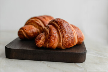 Delicious crispy croissant with chocolate with a cup of invigorating coffee on a light concrete background