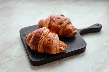 Delicious crispy croissant with chocolate with a cup of invigorating coffee on a light concrete background