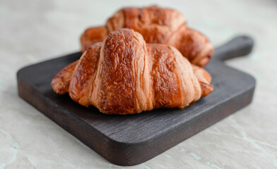 Delicious crispy croissant with chocolate with a cup of invigorating coffee on a light concrete background