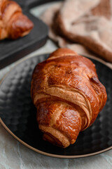 Delicious crispy croissant with chocolate with a cup of invigorating coffee on a light concrete background