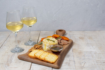 French camembert cheese baked in the oven with rosemary, cranberry and honey sauce, served with nuts and bruschetta on a wooden board. Served with white wine. Copy space