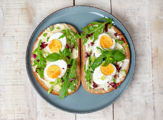 Boiled egg on bread with arugula, basil and pumpkin seeds cream in plate. Healthy food, keto diet, diet lunch concept.