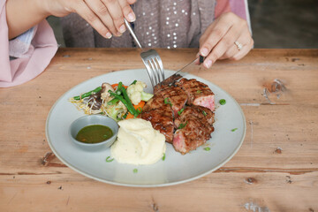 women eating beef steaks meat with vegetables on a plate 