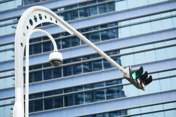 Fototapeta na wymiar CCTV security camera operating outdoor against city buildings 