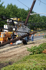 Electric utility repair crew on the scene of a broken wooden utility pole