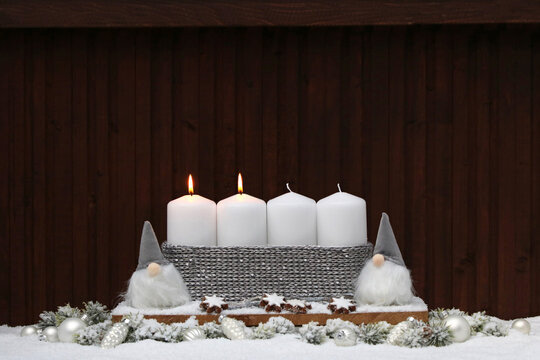 Fotoserie f&uuml;r die Adventszeit: Zweiter Advent zwei brennende Kerzen mit Zimtsternen und Weihnachtswichtel im Schnee.