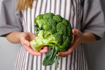 A woman holds green broccoli in her hands. Broccoli close up. Natural fresh organic vegetables. Healthy food, raw food diet. Vegetarian life. Proper nutrition. Ready to eat. Eco product
