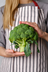 A woman holds green broccoli in her hands. Broccoli close up. Natural fresh organic vegetables. Healthy food, raw food diet. Vegetarian life. Proper nutrition. Ready to eat. Eco product
