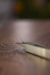 Silver eyelash extension tweezers close-up on a wooden background