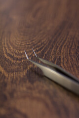 Silver eyelash extension tweezers close-up on a wooden background