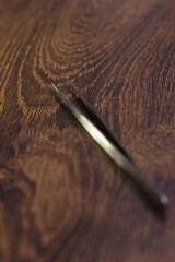 Silver eyelash extension tweezers close-up on a wooden background