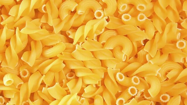 Uncooked Fusilli and Chifferi Rigati Pasta - Top View. Fat and Unhealthy Food. Classic Dry Macaroni, Slowly Rotating Background. Raw Different Macaroni Pasta Texture - Rotate Left