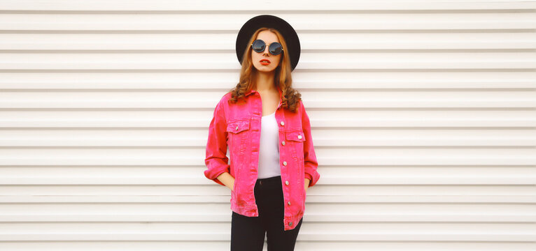 Portrait of stylish modern young woman wearing pink jacket, black round hat on white background, blank copy space for advertising text