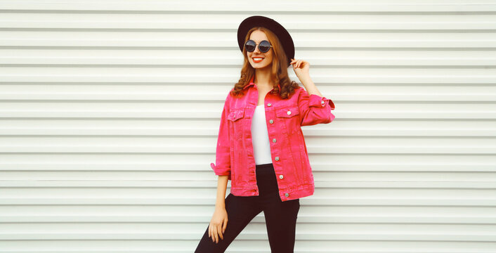 Portrait of stylish modern smiling young woman wearing pink jacket, black round hat on white background, blank copy space for advertising text