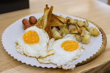 Fried eggs in a plate with potatoes, salad and bread for breakfast