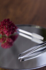 Eyebrow tweezers, brush and flower reflected on the mirror