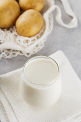 Potato milk and raw potatoes in a mesh bag. Plant based milk replacer and lactose free. Vegetable milk and sustainable lifestyle concept
