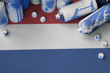 Netherlands flag and few used aerosol spray cans for graffiti painting. Street art culture concept