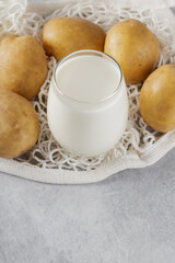 Potato milk and raw potatoes in a mesh bag. Plant based milk replacer and lactose free. Vegetable milk and sustainable lifestyle concept
