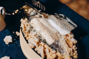 Fish baked in salt. The waiter cuts the fish into pieces. Restaurant concept.