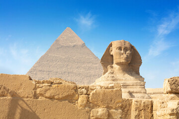 Egyptian Great Sphinx full body portrait with head, feet with all pyramids of Menkaure, Khafre, Khufu in background on a clear, blue sky day in Giza, Egypt empty with nobody.