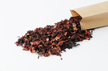Dried petals pomegranate flowers tea. Poured out of a paper bag on a white background. Flower drink, healthy food