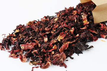 Dried petals pomegranate flowers tea close-up. Poured out of a paper bag on white background. Flower drink, healthy food