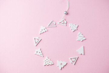 small white Christmas tree figurines laid out in the shape of a Christmas ball on a pink background with a place for text , Christmas concept, gifts,sale