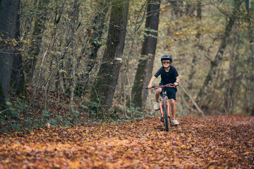 Enfant en v&eacute;lo dans les bois en automne