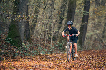 Enfant en v&eacute;lo dans les bois en automne