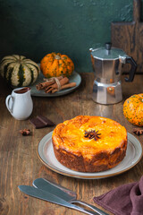 Round cottage cheese casserole with pumpkin layer on a ceramic plate on a brown wooden background. Pumpkin recipes. Thanksgiving, Halloween