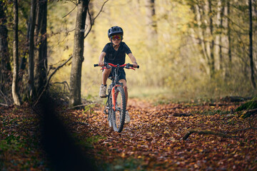Enfant en v&eacute;lo dans les bois en automne