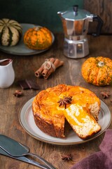 Naklejka na ściany i meble Round cottage cheese casserole with pumpkin layer on a ceramic plate on a brown wooden background. Pumpkin recipes. Thanksgiving, Halloween